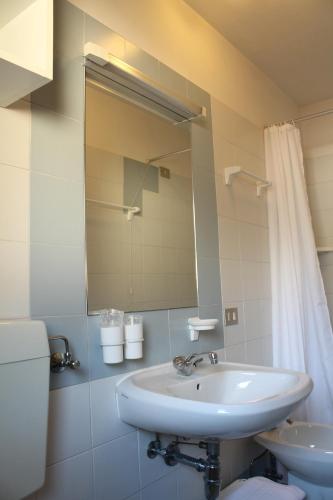 a bathroom with a sink and a toilet and a mirror at Hotel Villanova in Santo Stefano di Cadore