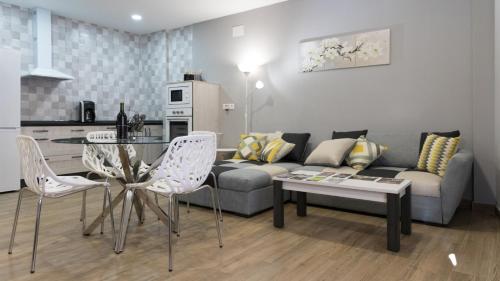 - un salon avec un canapé, une table et des chaises dans l'établissement Apartamentos La Chaparrina del Jerte, à El Torno