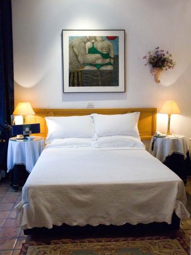a bedroom with a large white bed with two tables at Hotel Locanda Cairoli in Rome