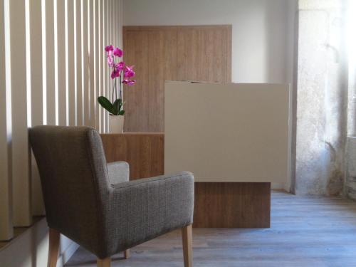 a chair in a room with a table and a flower at Rua Grande Hotel in Viana do Castelo