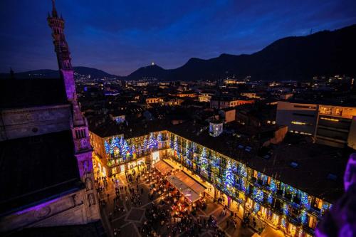 a city lit up at night with a building with christmas lights at Vitrum - Como Luxury Suites in Como