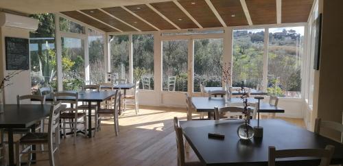 uma sala de jantar com mesas, cadeiras e janelas em Agriturismo Podere il Fornacino em Santa Luce
