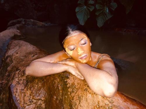 a woman laying on a rock in a bath tub at Termales el Escondite in Florencia