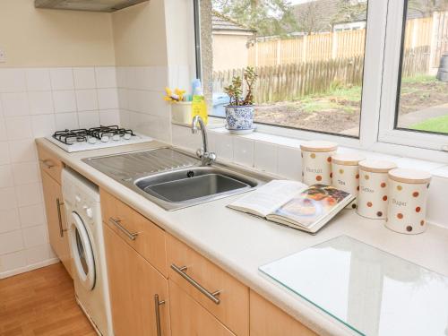 Una cocina con fregadero, estufa y ventana. en Wynnville, en Embsay