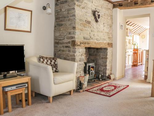 a living room with a chair and a fireplace at Garden Cottage in Ludlow