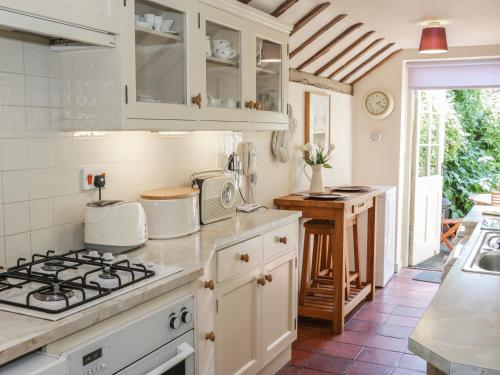 a kitchen with white cabinets and a stove top oven at Garden Cottage in Ludlow
