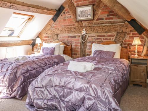 zwei Betten in einem Zimmer mit einer Ziegelwand in der Unterkunft Garden Cottage in Ludlow