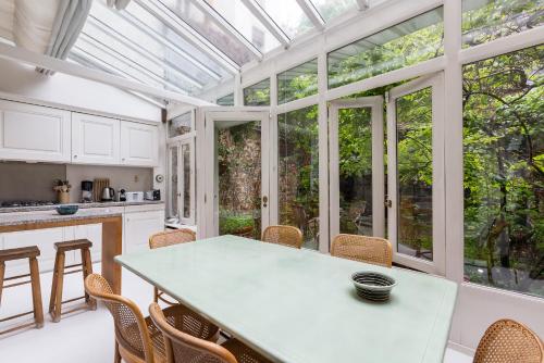 une véranda avec une table et des chaises dans une cuisine dans l'établissement Veeve - Charming Townhouse near Parc Montsouris, à Paris