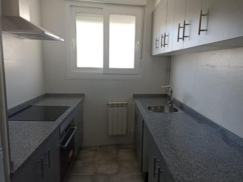 una pequeña cocina con fregadero y ventana en Apartamento Barbadillo - Redmansur, en Cáceres