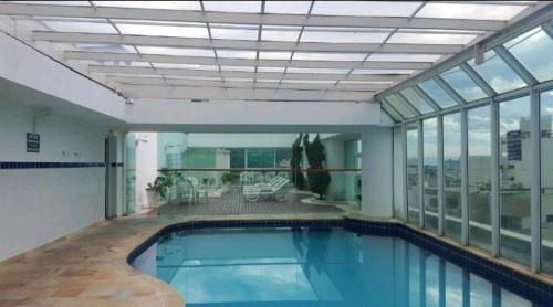 a large swimming pool in a large building with windows at Guarujá Flat in Guarujá
