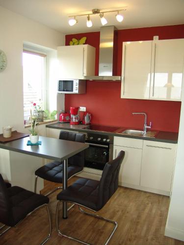 a kitchen with red walls and a table and chairs at Strandresidenz-Rosengarten-Wohnung-Nr-301 in Büsum