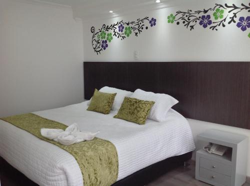 a bedroom with a bed with green and purple flowers on the wall at Hotel Burana in Bogotá