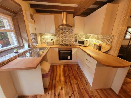 a kitchen with white cabinets and a wooden floor at Heptonstall Cottage, Heptonstall, Hebden Bridge in Heptonstall