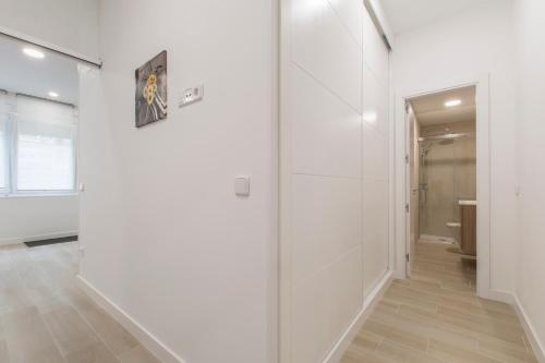 un pasillo con paredes blancas y una puerta de cristal en 4Torres Homes - Carmen en Madrid