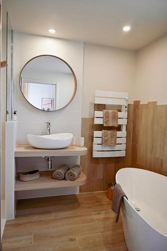 une salle de bain avec une baignoire, un lavabo et un miroir dans l'établissement L'envie, à Saint-Gilles-Croix-de-Vie