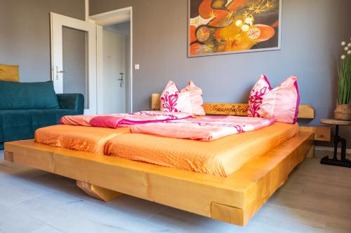 una cama de madera con almohadas rosas encima. en Whg./flat am Großen Garten in Dresden, en Dresden