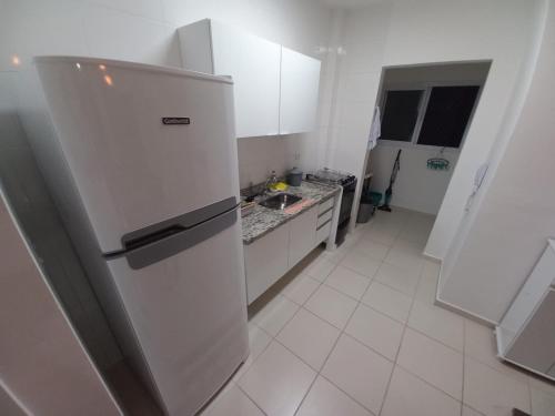 a white kitchen with a refrigerator in a room at APTO FAMILIAR EM BERTIOGA JARDINS DO INDAIÁ A 500 M Praia in Bertioga