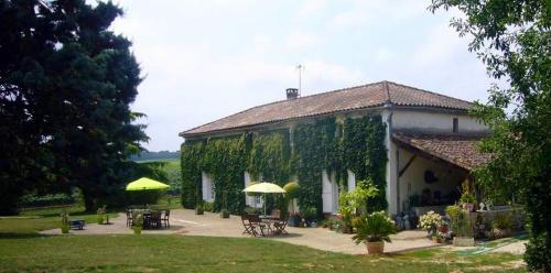 un edificio cubierto de vides con mesas y sombrillas en Le Château de Roquebère, en Condom