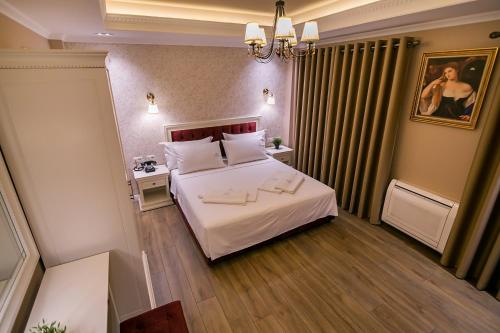 a hotel room with a bed and a chandelier at Legacy Boutique Hotel in Korçë