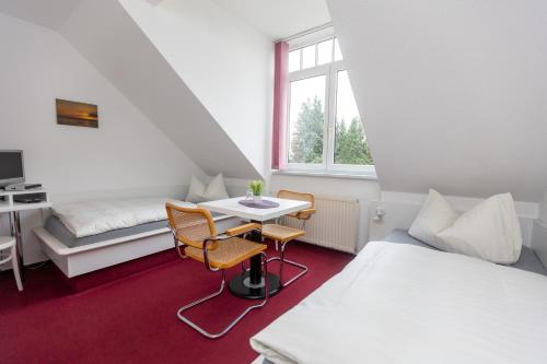 a room with two beds and a table and chairs at Pension Zum Lindeneck in Lübz