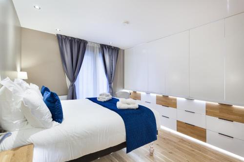 a bedroom with a large bed with blue and white pillows at Suite Appart Place Versepuy in Chantilly