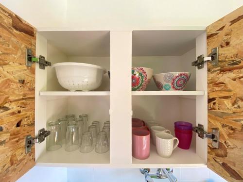 a cupboard filled with bowls and vases at The Beachhouse Apartments in Vaia