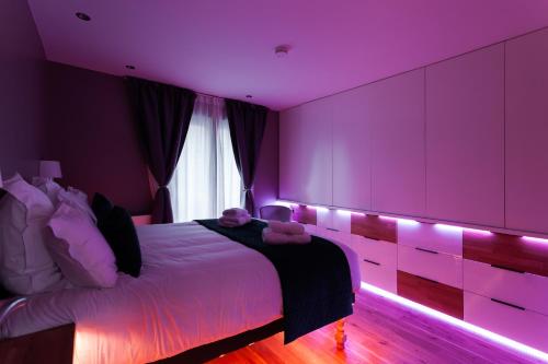 een paarse slaapkamer met een bed met verlichting bij Suite Appart Place Versepuy in Chantilly