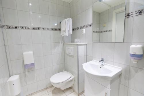 a white bathroom with a toilet and a sink at Skjåk Turistheim in Skjåk