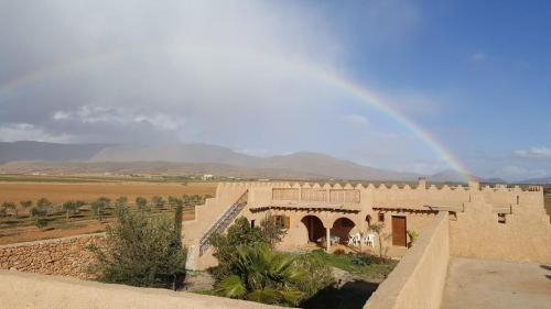 a rainbow in the sky over a building in a desert at Ksar Montana Gîtes, Chambres piscine in Taforhalt