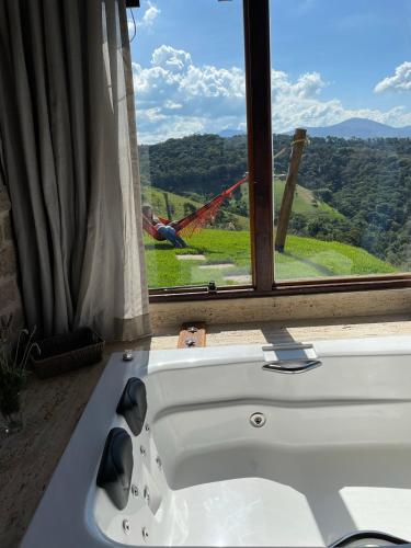 a white bath tub in a room with a window at Chalé Terrarum in Santo Antônio do Pinhal