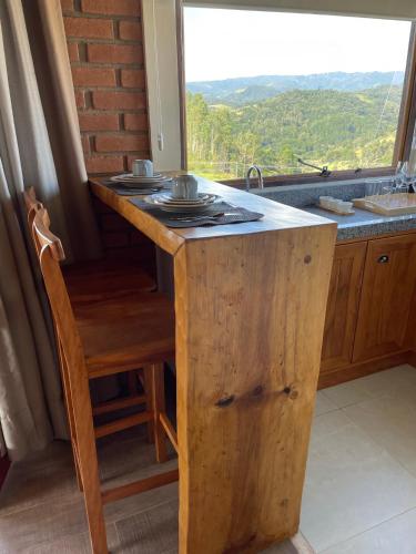 a kitchen with a island with a stove and a window at Chalé Terrarum in Santo Antônio do Pinhal