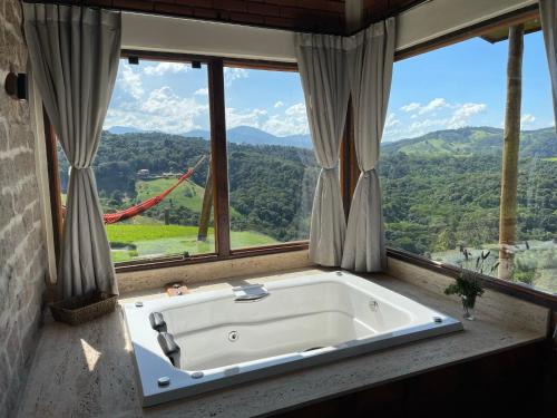 a bath tub in a room with a large window at Chalé Terrarum in Santo Antônio do Pinhal