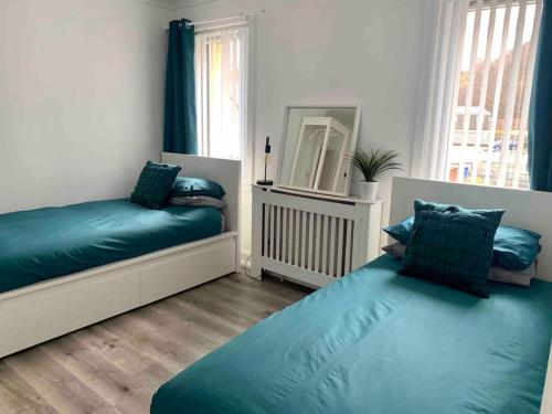 1 dormitorio con 2 camas azules y espejo en Nevis Rooms - Self check in with free onsite Parking en Inverlochy