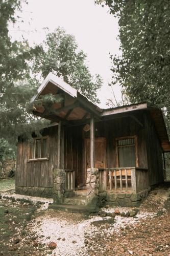 a small wooden cabin with a porch and windows at Hotel & Spa Escondite de la Montaña in Sabana Redonda