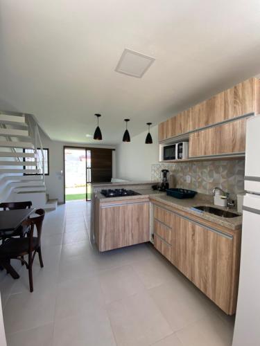 a kitchen with wooden cabinets and a dining table at Flats Sol e Mar in São José da Coroa Grande