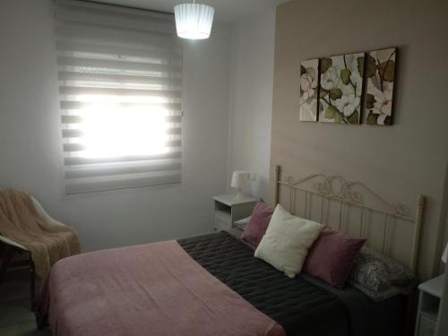 1 dormitorio con 1 cama con almohadas moradas y blancas en Apartamento Rotasol en Rota