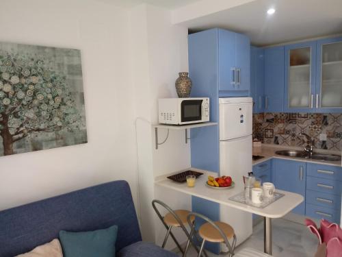 una pequeña cocina con armarios azules y microondas en Apartamento Rotasol, en Rota