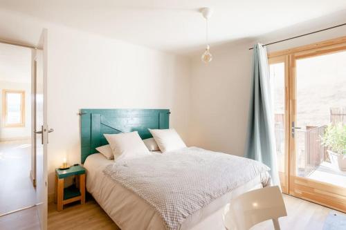 1 dormitorio con 1 cama con cabecero verde y ventana en La maison de Gaston au cœur du Luberon, en Villars
