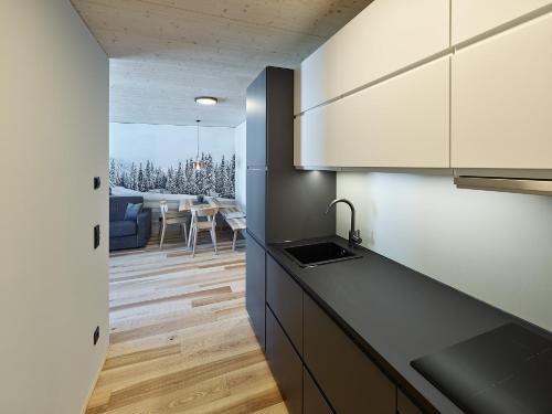 a kitchen with white cabinets and a dining room at DER*ADLER Apartments in Schoppernau