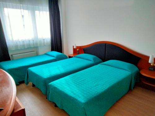 two beds in a room with green sheets at Hotel Donizetti in Lallio