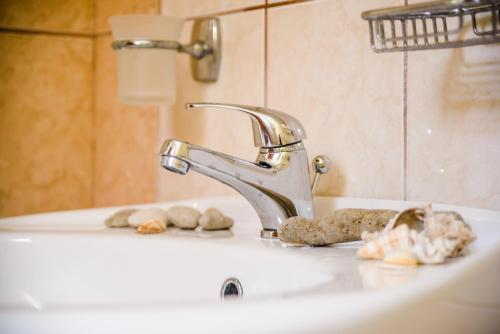 a bathroom sink with a faucet and rocks on it at Light House in Katelios