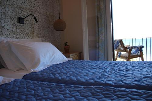 a bed with a blue blanket and a chair in a bedroom at Dassia Beach Hotel in Dassia