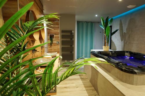 baño con bañera negra y planta en LA DOLCEVITA SPA Chambre privative, en Besançon