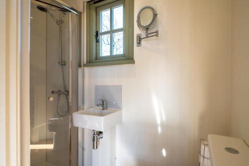 a white bathroom with a sink and a shower at Scalderskew Shepherds Hut in Gosforth