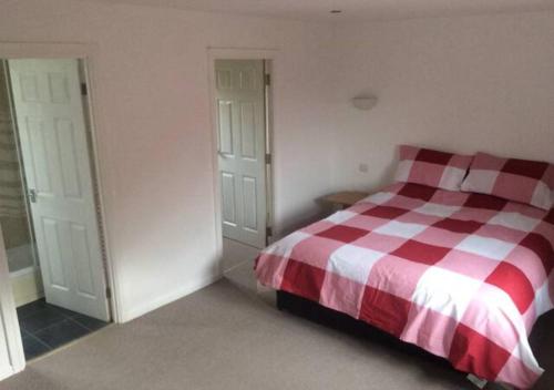 a bedroom with a bed with a red and white checkered blanket at 6 Bedroom House For Corporate Stays in Kettering in Kettering