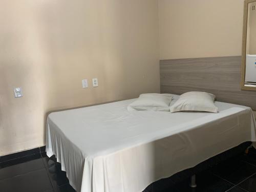 a large white bed with two pillows on it at Porto Seguro Hotel - Porto Velho in Porto Velho