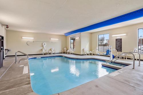 uma piscina num quarto de hotel com cadeiras e mesas em Cobblestone Hotel & Suites - Little Chute em Little Chute