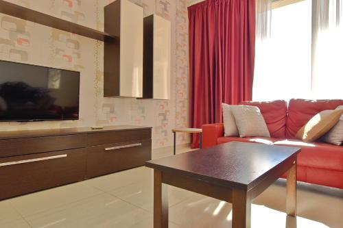 a living room with a red couch and a tv at 101 Moroni by Cast Renting in Il-Gżira