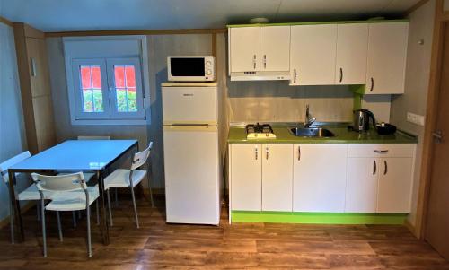 a kitchen with a table and a white refrigerator at Camping Igara de San Sebastian in Donostia-San Sebastián