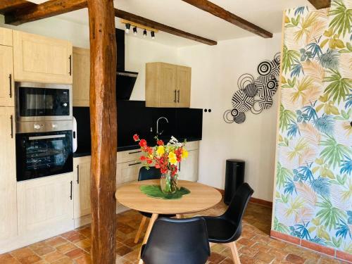 a kitchen with a table with flowers on it at Maison de campagne avec cheminée et extérieur in La Neuville-aux-Bois